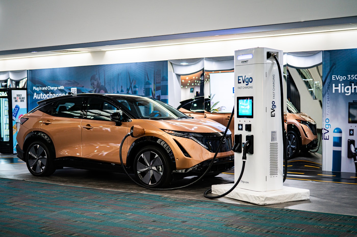 Vehicles on a showroom floor beside a charging unit